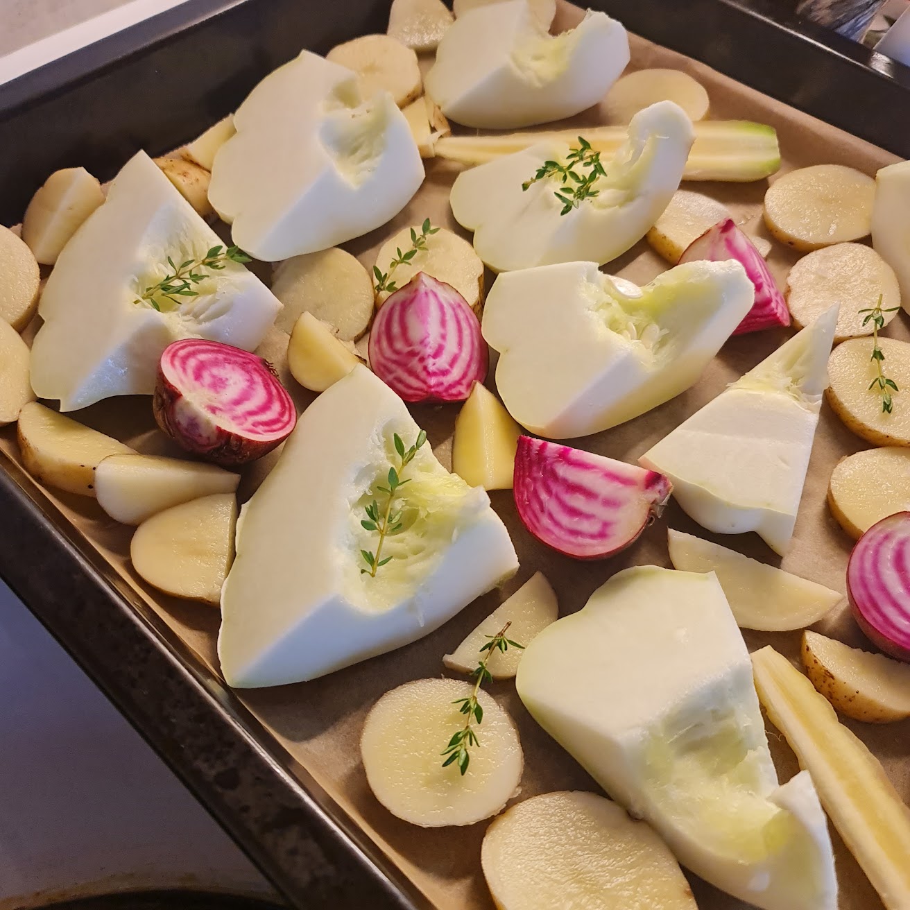 An oven tray filled with vegetables cut into large chunks.